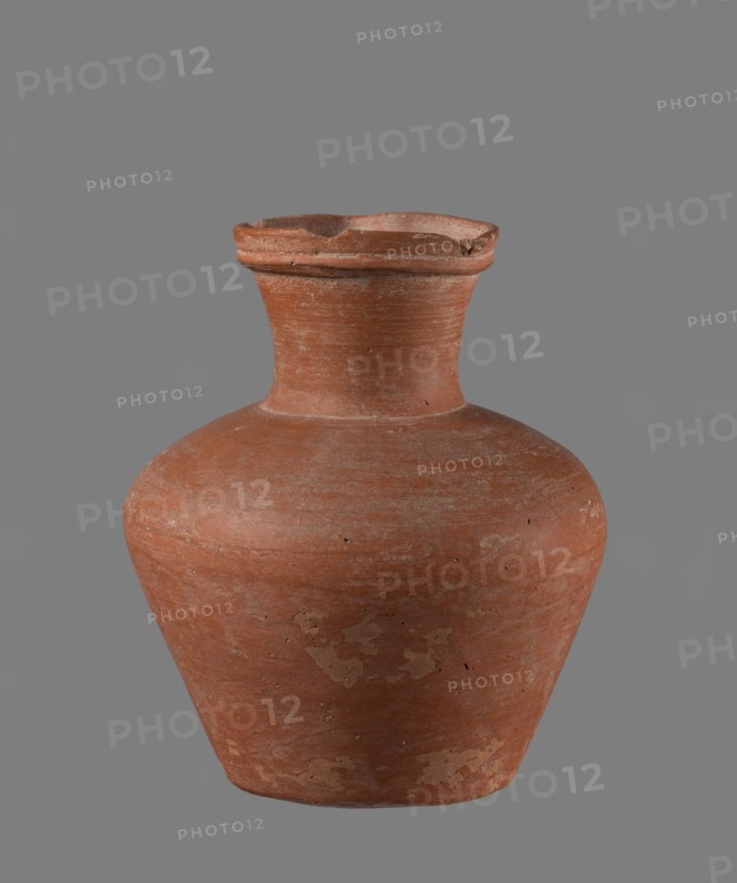 Jug with biconical belly. Vessel is widest at about half its height; shoulders broad, not very sloping. Neck wide, slightly widening toward the spout, its height about 1/3 of total. Spout profiled, irregular, slightly raised and extended on one side forming a small secondary spout; almost triangular in cross-section with ~1 mm indentation at centre of outer profile. Bottom very slightly rounded. Made of Nile clay NB1, Vienna System. Neck was made separately and joined; joint traces erased. Outer surface smoothed, covered with engobe and polished. Inner surface smoothed except for the neck, which was also covered with engobe and polished. Color reddish-brown. Condition: quite well preserved; rim slightly chipped in two places; engobe worn off in places on outer surface. Provenance: Edfu — local workshop. Chronology/style: Old Kingdom comparative types ca. 2686–2181 BC. Comparative example: Reisner, Mycerinus, fig. 69 type XIX, XX, vessel height 17.4 cm, rim Ø 8.1 cm, body Ø 15 cm, base ...