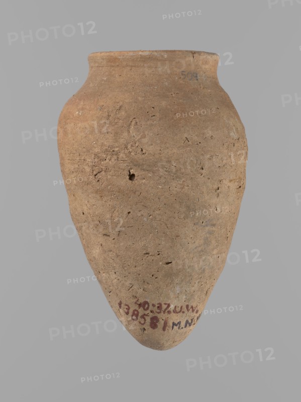 Vessel with hieratic inscription. Conical clay vessel tapering toward a pointed bottom; irregular shape, widest approx. 3/4 of the height. Narrow, only slightly sloping shoulders; short, wide neck; very gently rounded, slightly flaring rim. Handcrafted: upper part shoulders, neck, rim turned. Smooth surface, externally probably covered with a layer of engobe. Made of Nile clay NB2 Vienna System. Remains of a hieratic inscription in black in the lower part of the belly. Complete, well preserved. Old Kingdom, Edfu. Height 12.5 cm; rim diameter 5.4 cm; belly diameter 8 cm. Comparative references: Petrie Dendera, Abydos, Reisner Mycerinus; Naga ed-Der, Brunton Qau and Badari, Mace Naga ed-Der II, Keiser/Avila/Dreyer/Jaritz/Laskowska-Kusztal, ca. 2686–ca. 2181 BC., A single large earthenware vessel fills the frame, shown against a plain light gray background; the vessel has an ovoid body that tapers to a rounded point at the bottom and widens into a short neck with a slightly flared rim at ...