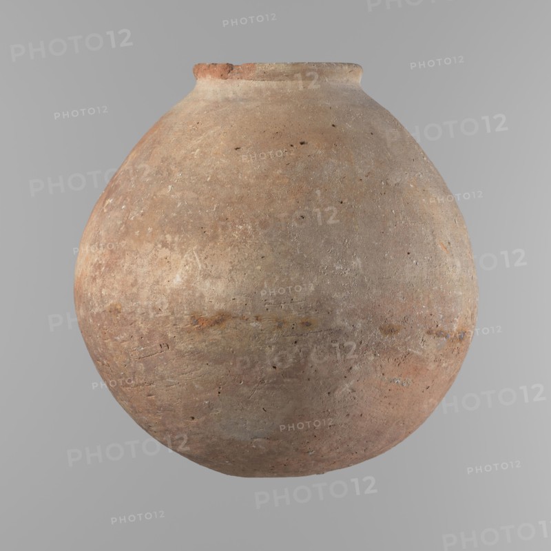 Vessel, Vessel with an almost spherical belly, widest about 1/3 of the vessel's height. Sloping shoulders. Neck poorly defined – very short and wide. Rounded, slightly flaring rim. Rounded bottom. Made of Nile clay NB. Surface smooth; outer surface finished to about half its height with a knife or similar tool. A rather indistinct cord impression around the widest diameter of the belly. Colour light red. Chipped rim and traces of salting in places over the entire surface. Comparative typology: similar to types II–III Old Kingdom, ca. 2686–2181 BC, provenance Edfu. Dimensions: height 24.9 cm; rim diameter 10.3 cm; body diameter 24.2 cm., A large round clay vessel with a narrow neck and a slightly flared rim, shown against a plain gray background; the vessel has a rough, weathered surface with visible pitting and texture, and an overall color palette of earthy browns and muted reds with patches of pale beige and hints of gray and rusty orange.