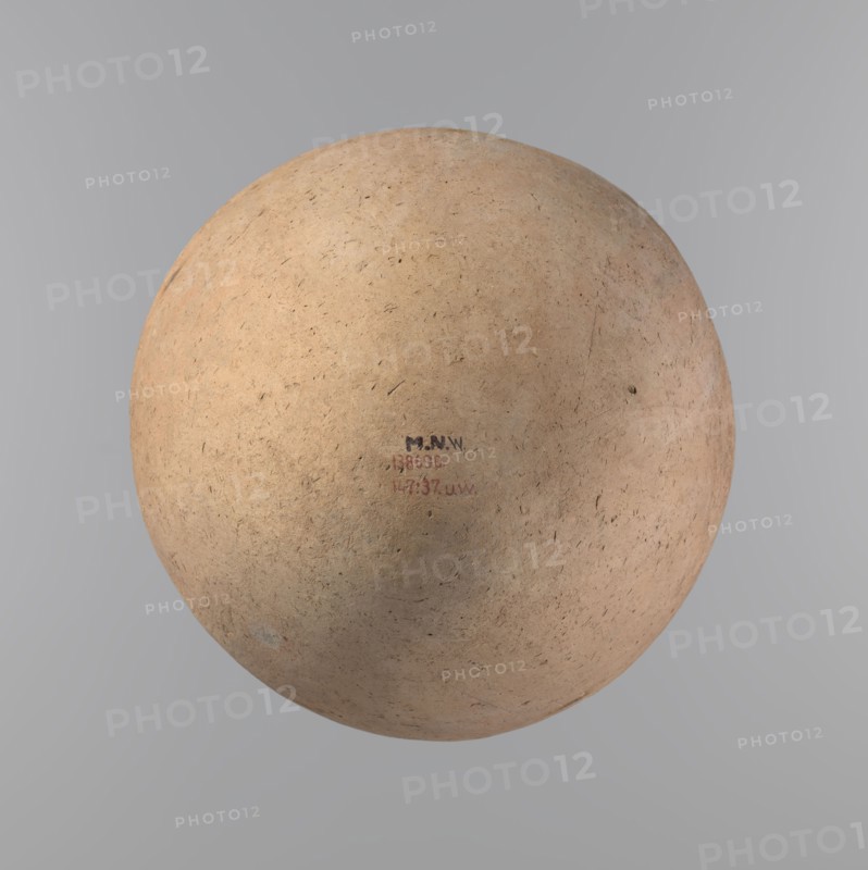 Vessel of an ovoid, slightly downward-stretched shape, widest at about 2/3 of the height. Broad, sloping shoulders, very short, wide neck. Roller-shaped rim, oval in cross-section, slightly flaring. Rounded bottom. NB2 clay according to the Viennese System with a significant amount of organic admixture. The vessel is hand-made from two parts and joined at about 2/3 of the height, turned in the upper part. Surface leveled covered with a layer of engobe?. Traces of a white substance in places on the outer surface of the body and on the rim. Vessel colour – beige. Well-preserved vessel. Ca. 2686–2181 BC; Old Kingdom, Edfu. Vessel; height 34.6 cm, diameter 11.6 cm rim, diameter 29 cm body., A roughly spherical, textured object with a worn, earthy surface fills the center of the image, showing colors of light tan, beige, pale brown, and hints of muted peach and gray, with small dark specks and fine scratches across its surface; the background is a smooth gradient of gray tones.