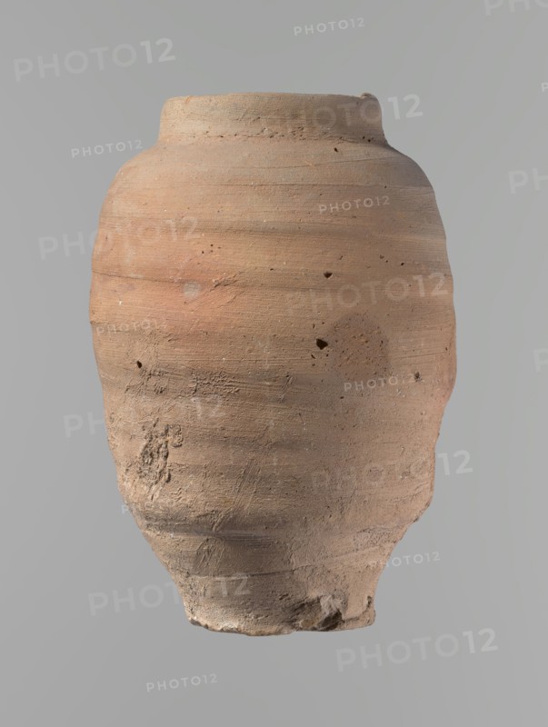 Vessel, Beer jug of a slightly irregular, conical shape with a wide, very short neck and a flat bottom. Flat, straight rim. Wheel-made from Nile clay of type NB2-ND Vienna System. Bottom cut off with string; clear potter's fingerprints around the bottom. Surface even. Clay color red. Vessel complete, fairly well preserved, with minor damage to the rim and small chips on the surface. ca. 1550–1069 BC; New Kingdom, Edfu. Vessel. Height 24.4 cm; rim diameter 9.8 cm; body diameter 16.3 cm; bottom diameter 8.5 cm., A rounded, slightly irregular clay vessel with a narrow base and a wider shoulder is shown against a plain background; the vessel has a rough, textured surface with visible tool marks, small pits, and areas of surface abrasion, and its color palette includes shades of terracotta, light brown, pale beige, and hints of gray.
