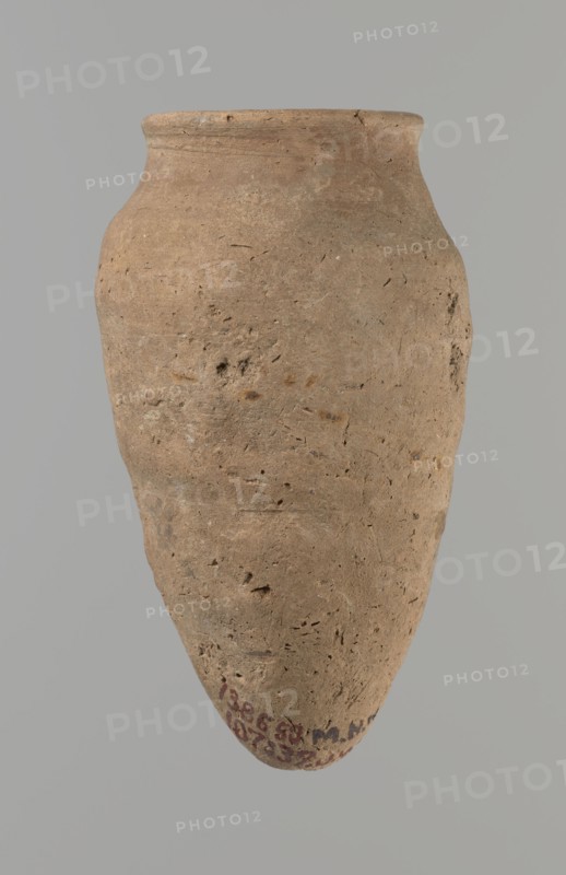 Vessel with hieratic inscription, Egyptian pottery, ceramic conical vessel tapering towards the bottom, irregular, widest at approx. 3/4 of the height. Narrow, slightly sloping shoulders; short, wide neck; very gently rounded, slightly flaring rim; pointed bottom. Handcrafted; upper part shoulders, neck, rim turned. Smooth surface, externally probably covered with a layer of engobe. Made of Nile clay NB2 Vienna System. Remains of a hieratic inscription in black on lower part of the belly. Well preserved with slight damage to the rim. Analogies: Petrie, Dendera, Hope, Akhmim, Reisner, Brunton, Mace, Keiser et al.; earlier dated to the 4th–5th Dynasty; ca. 2686–ca. 2181 BC; Old Kingdom, Edfu. Dimensions: height 13.9 cm; lip diameter 5.9 cm; max diameter 8 cm., A single earthenware jar with a rounded body tapering to a pointed base, shown against a plain gray background. The vessel's surface is rough and pitted with visible irregularities and small indentations. The rim is slightly flared...