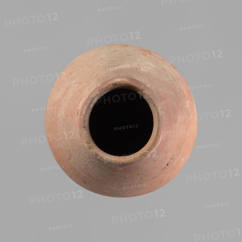 Vessel with an ovoid belly, a wide short neck and a rounded bottom. Straight, upturned rim. Wheel-made from Nile clay of type NB2 Vienna System. Surface levelled and outer surface covered with engobe. Outer surface red; inner surface yellowish-brown. Firing hole at the widest circumference, approx. 1 cm diameter. Well-preserved. ca. 1550–1295 BC; New Kingdom, 18th Dynasty. From Deir el-Medina. Vessel; height 27 cm; rim diameter 11 cm; body diameter 20.5 cm., A round clay vessel viewed from above with a dark open interior, showing a rim and a rounded body with a textured surface in shades of reddish-brown, terracotta, beige, and hints of gray, set against a plain light gray background.