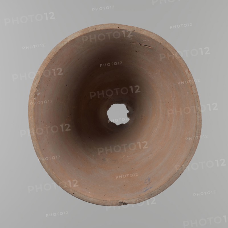 Bowl. Vessel flower pot with a conical shape and a flat bottom. Irregular walls. Straight, flat, slightly flaring, asymmetrical rim. Made on the wheel of Nile clay type NB2 Vienna System. Irregular bottom, cut off with a string; 3.2 cm diameter hole in the bottom. Potter's fingerprints as clear indentations in the lower part of the vessel next to the bottom. Smooth surface. Reddish-brown clay. Condition good, with only minor damage to the rim. ca. 1550–ca. 1069 BC New Kingdom, Deir el-Medina. Height 18 cm; rim diameter 15.8 cm; bottom diameter 9.5 cm., A view looking into a round, hollow, cylindrical object made of clay with a rough, matte surface showing earthy brown and terracotta tones, with darker brown areas toward the center and subtle variations of reddish-brown and beige along the inner walls; the rim shows a few small chips and rough edges in similar brown colors, and a small irregular hole is visible at the far end revealing a pale gray background; the surrounding background ...