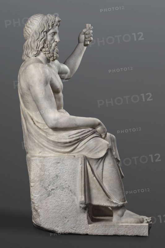 Statue of Jupiter of the Capitoline type, unknown Roman workshop, Jupiter mythology, Zeus mythology, Roman sculpture, Roman copy after a Hellenistic variant of Phidias's statue of Zeus the Olympian. Zeus seated on a throne set on a rectangular base. Zeus sits stiffly with his torso slightly back. His raised left hand holds a scepter. His right hand rests casually on his right knee. The right foot is slightly forward. The legs are covered with a himation, which also covers the back and left shoulder. The muscular torso, strongly developed at the shoulders, has naturalistic modeling. The head is disproportionately large, and the face is perfect with a slightly open mouth. The hair on the head is parted from the center anastole. The beard is thick, arranged in strands on the sides and in curls on the chin. Late 2nd–3rd century, Roman Empire 27 BC–476 AD, sculpture, weight 930 kg., A seated marble statue of a bearded man shown in profile, with wavy hair and a textured headband, his upper b...