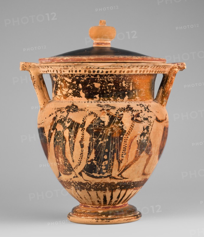 Column krater with lid, unknown Attic workshop. Black-figure krater with lid. Red clay, tinted with ochre. Black varnish with a muted lustre, fading to brown in places. The rim is decorated with a radial ornament and a schematic ivy sprig; the shoulders bear a series of vertical lines. The belly is decorated with figural scenes. Side A: Dionysus holding a cornucopia, accompanied by a satyr and a maenad. Side B: an archer flanked by two helmeted hoplites with round shields. Lid with a pomegranate-shaped handle, decorated with an ivy sprig on the rim. 520–510 BC, Attica. Vessel type: column krater. Weight 1.382 kg. Diameter 19.2 cm 22.5 cm with vices. Height 21.4 cm 22.6 cm with vices., An ancient-style ceramic vessel with a lid and two handles is shown, featuring a rounded body on a flared foot and a knobbed lid; the surface shows worn painted figures and patterns in dark brown to black against a warm terracotta background with areas of lighter beige where the paint has chipped, and the...