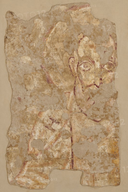 Wall painting: Saint John the Apostle, Nubian workshop; wall painting, John the Evangelist Saint; ?–ca. 100 - iconography. Depicted frontally, a preserved fragment showing the head and left shoulder of the figure. The head is surrounded by a circular yellow halo outlined by a purple and white stripe. The contours of the face and features are painted with black paint. High forehead, regular eyebrow arches, large almond-shaped eyes, wide open, with marked irises and pupils; a straight nose ending in a wedge; large protruding right ear left ear missing. Long white beard ending in a pointed tip. On the white robe, the Greek letter eta H is visible on the figure's right shoulder. The folds of the robe are marked with wide yellow and purple lines. Original plaster: 82 x 36 cm; 8th century, Faras. Dimensions: 105 x 78.5 -79 x 4.5 cm; wall painting height 105 cm, width 78.5–79 cm, depth 4.5 cm; original plaster height 82 cm, width 62 cm., A weathered fragment of painted plaster with an irregul...