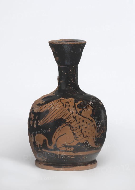 Lekythos with a sphinx. Unknown Attic workshop. Ceramic, Attic red-figure lekythos. A small lekythos with a narrow neck, round belly on a round foot. Central front of the belly decorated with an image of a sphinx; back of the vessel has worn finials. 1st half of the 4th century BC. Vessel. Height 9.4 cm; diameter 6 cm., A rounded ceramic vessel with a narrow neck and flared rim sits against a plain light background; the surface shows a mainly black glaze with worn areas revealing a reddish-brown clay underneath, and the body is decorated with a reddish-brown figure of a winged animal with a long tail and spotted body; the neck and rim are black with scattered wear, and the base shows exposed reddish-brown clay and signs of age.