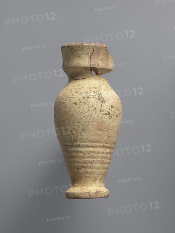 Water vessel qulla. Ovoid with elongated belly; edge of foot protrudes outward. Short, wide neck transitions into a higher, slightly flared section above a sharp break in the wall. Inside the neck a strainer made by puncturing holes in the clay before firing. Entire surface covered with cream-yellow whitewash. Medium-porous Nile clay. 2nd half of the 5th–6th century. Vessel for storing water. Height 17.2 cm; width 9.3 cm; outer rim diameter 7 cm; base diameter 5 cm. Egyptian workshop; Coptic, household vessel., A worn ceramic vessel with a rounded body narrowing toward a small foot and a short neck topped by a broken rim is centered against a plain gray background; the vessel shows a rough, pitted surface with areas of flaking and a mottled palette of beige, tan, light brown, and hints of reddish-brown, and several horizontal incised rings around the lower body.