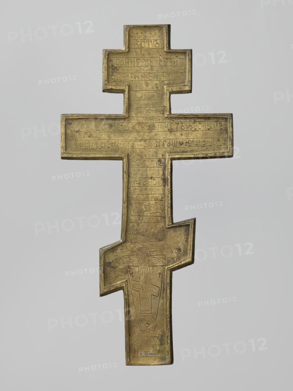 Cross: Crucifixion of Christ. Old Believers workshop. Brass cast eight-pointed cross with rough casting; background enamel in navy blue, sky blue, and white. Obverse: image of the Crucifixion — Christ suspended on the cross; below, a grotto with Adam's skull and the tree of Seth; at the footstool level, a view of Jerusalem; on the long beam beside Christ, the sun and the moon; in the upper part, a bust-like image of the Lord of Hosts with the dove of the Holy Spirit below; ornaments, inscriptions, and halo. Reverse: engraved prayer to the Holy Cross and an image of an eight-pointed cross. Iconography: Jesus Christ; Lord of Hosts; God the Father; Holy Spirit; Crucifixion; Adam; Golgotha; skull; instruments of the Passion; sun; moon; Jerusalem; ornaments; inscriptions. 19th century, Russia. Dimensions: height 34.3 cm, width 17.3 cm., A metal cross with an elongated shape and a stepped, off-center lower arm, shown against a plain light gray background; the cross has a weathered golden-bro...