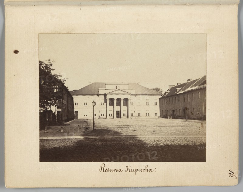 Resursa Kupiecka Former Mniszech Palace at Senatorska Street, Mniszech Palace Warsaw, Warsaw Masovian Voivodeship; Beyer, Karol 1818–1877 photographer/creator; Méyet, Leopold 1850–1912 author; cobblestones, street lamps, Senatorska street; 1861–1863; photography, nature photography; photographic print: height 6.2 cm, width 8 cm; backing: height 11.3 cm, width 8.8 cm., A sepia-toned photograph mounted on a light beige board shows a wide cobblestone square flanked by buildings, with a large classical building centered in the background featuring a triangular pediment and columns at its entrance; a tall street lamp stands near the middle foreground, and a few trees and two rows of lower buildings frame the square on the left and right. The visible colors are beige, brown, dark brown, and off-white.
