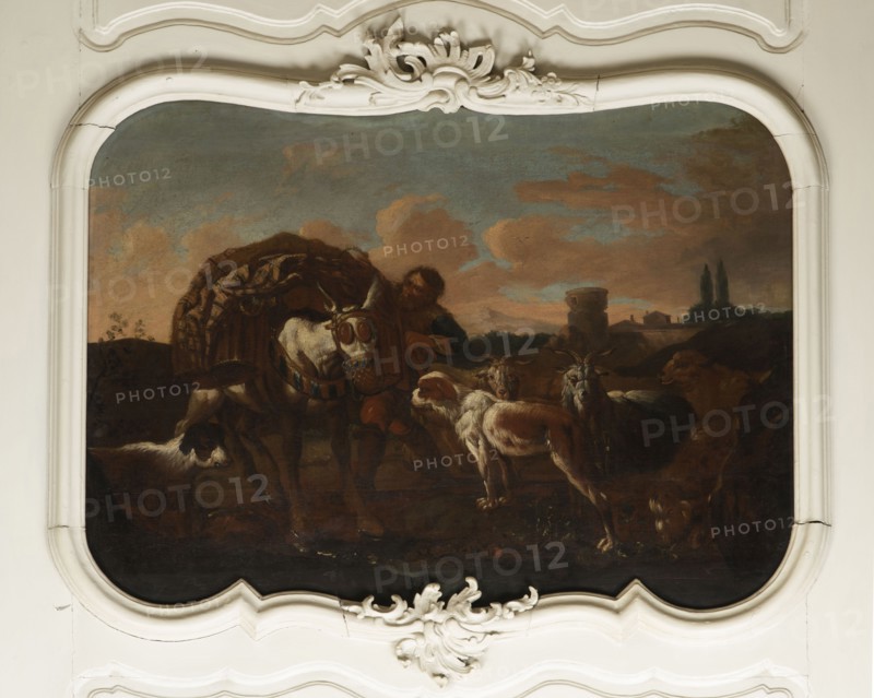 Shepherd's Scene with a Laden Donkey, Roos, Philipp Peter 1657–1706 painter. General tones of brown against a grey-blue sky with pink clouds and a slightly marked mountain range. The second plan on the right consists of buildings and clumps of trees. The foreground is a genre scene: next to a donkey laden with baskets a peasant secures the load; nearby are two dogs, two goats and two rams. 18th century, Italy; overdoor. Height 92.0 cm, width 127.5 cm., A painted scene set within an ornate white frame shows a pastoral group with a few animals and a person. The colors include browns, creams, muted greens, greys, blues, and touches of reddish tones. A central light-colored horse with decorative harnessing stands near a man partly obscured and wearing darker clothing. Several goats and sheep with cream, brown, and grey fur gather nearby, and a dark-colored dog is visible at the lower left. The background displays a landscape with rolling hills, a distant building and towers, and a sky fill...