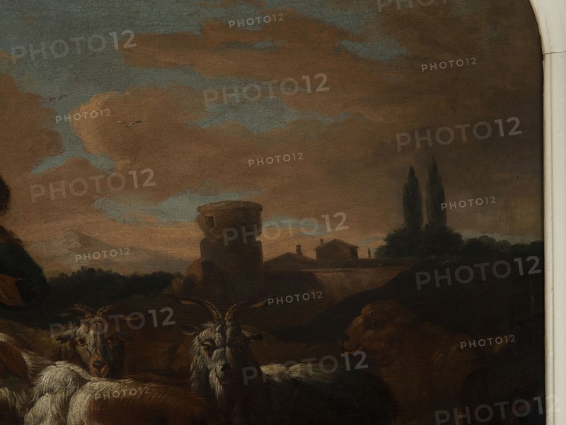 Shepherd's Scene with a Laden Donkey, Roos, Philipp Peter 1657–1706, painter. General tones of brown against a grey-blue sky with pink clouds and a slightly marked mountain range. The middle distance on the right shows buildings and clumps of trees. The foreground is a genre scene: next to a donkey laden with baskets a peasant secures the load; nearby are two dogs, two goats and two rams. 18th century, Italy. Overdoor. Height 92.0 cm, width 127.5 cm., A painted scene showing a dusky sky with clouds in shades of brown and blue, a group of animals in the foreground including goats and sheep with fur tones of white, gray, brown, and tan, a stone structure and small buildings silhouetted against the horizon in darker brown and muted earth tones, a pair of tall, dark trees near the buildings, and a pale vertical border at the far right.