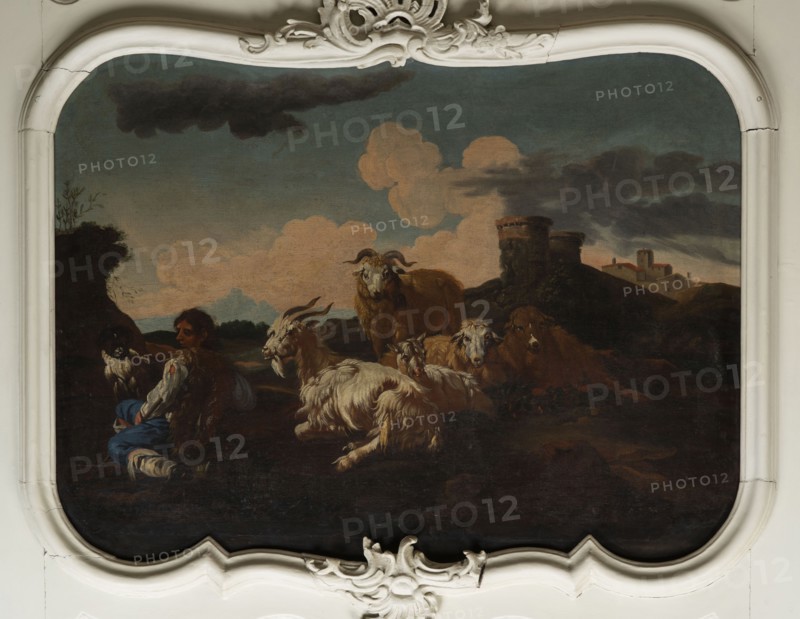 Shepherd Scene with a View of the Castle, Roos, Philipp Peter 1657–1706 painter. Multicolored composition with dominant shades of brown against a blue sky with white clouds and a distinct pink glow. In the foreground, the central group consists of two goats, a male and a female, lying down, with a male goat standing behind them. On the left, a slope, a dog, and a shepherd sitting in half-profile, wearing a brown sheepskin coat, blue trousers, a white shirt, and stockings. On the right, in the background on a hill, two cylindrical buildings; behind them, castle buildings. 18th century, Italy; overdoor; height 92.0 cm, width 115.0 cm., A painted scene shows a group of animals including several goats and a few sheep with varied fur textures and colors such as white, cream, brown, and tan gathered on a dark foreground; a person sits among them wearing clothing with blue, white, and brown tones; the middle ground contains a rounded stone structure and low hills in dark brown and green, and ...