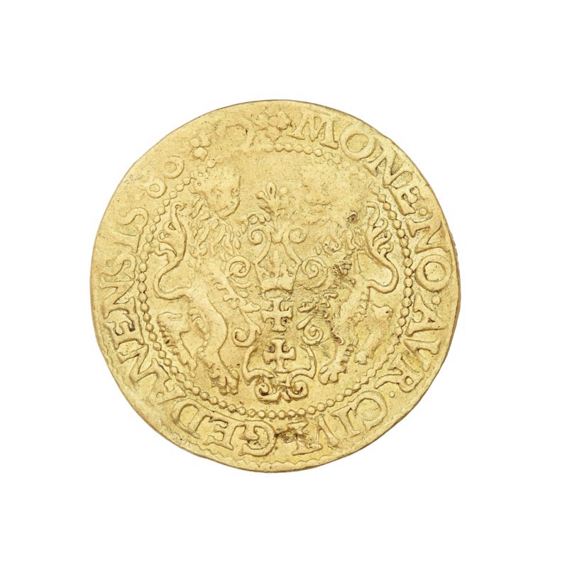 Gdansk ducat, Stefan I Batory king of Poland; 1575–1586, author; Poland; Gdansk; coin, A single round coin with a worn, embossed design fills the center of the image; the coin is predominantly gold in color with areas of darker, slightly brownish wear. The surface shows ornate, raised decorative elements including flowing scrollwork and shield-like forms, and there are two mirror-like animal figures flanking the central motif. A beaded circular border runs near the rim, and the coin edge appears slightly irregular and aged. The background around the coin is plain white.