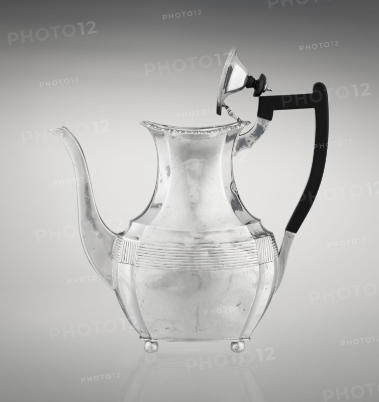 Coffee pot by Harris, CS & Sons London; goldsmiths' firm, fl. 1817–1933 and Charles Stuart Harris maker, fl. 1852–1897. Purchased; scrap - purchased. Pear-shaped, ribbed coffee vessel with godron ornaments; supported on four profiled, ball-shaped legs. Belly decorated with a band formed by narrow half-cylinders and grooves. High spout-shaped side handle; wooden handle contemporary addition set on the axis in silver sockets. Upper edge edged with godron band; hinged lid domed in the center, topped with a bowling-pin finial. Dated 1895/1896. Great Britain, London. Vessel. Height 21.2 cm; width 18.5 cm; depth 10 cm; weight 640 g., A reflective metal pitcher with a curving spout and a high, flared neck sits against a smooth gradient background; the body is rounded with ribbed horizontal decoration around the midsection and rests on small round feet, while a hinged lid is propped open and a dark, curved handle attaches to the side. The visible colors are metallic silver on the pitcher, blac...