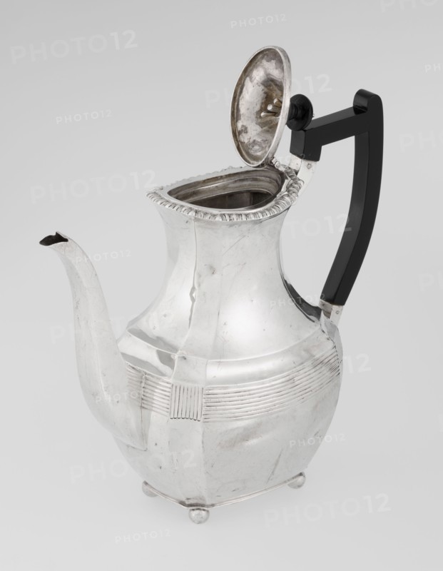 Coffee pot; maker: Harris, CS & Sons London, goldsmiths' firm, active 1817–1933 and Harris, Charles Stuart maker, fl. 1852–1897; provenance: purchased scrap - purchased. Pear-shaped, ribbed coffee vessel supported on four ball-shaped profiled legs; belly decorated with a band of narrow half-cylinders and grooves; godron ornaments; high side spout-shaped handle and a contemporarily added wooden axial handle set in silver sockets; upper edge edged with a godron band; hinged lid domed in the center, topped with a bowling-pin finial. Dated 1895–1896. London, England. Materials/technique: silver with wooden handle; height 21.2 cm, width 18.5 cm, depth 10 cm; weight 640 g., A shiny metal pitcher with a curved spout and an open hinged lid showing the interior, a dark handle attached to the body with a rounded knob near the lid, a rounded body with horizontal decorative ridges and a slightly flared neck edged with a scalloped rim, small rounded feet at the base, and visible scratches and tarni...