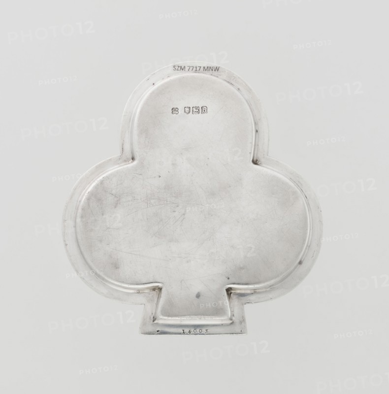 Tray, Hukin & Heath Birmingham; London; goldsmiths' firm; fl. 1855–1953 maker, Heath, John Thomas & Middleton, John Hartshorne makers, club-shaped tray with a smooth mirror surrounded by a raised half-cylinder with an edge decorated with an ornament of diagonal godrons; godron ornaments; scrap; 1897/1898; Great Britain, England, London; table accessory; height 1.1 cm, width 12.5 cm, depth 11.9 cm, weight 86 g., A metallic object with a smooth, slightly scuffed surface in a pale silver color, shaped like a rounded trefoil with a short rectangular tab at the bottom; the metal shows a few fine scratches and subtle darker smudges, and the object sits against a plain light gray background.