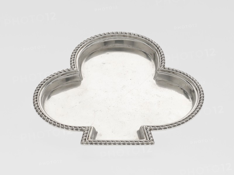 Tray, Hukin & Heath Birmingham; London; goldsmiths' firm; fl. 1855–1953 maker, Heath, John Thomas & Middleton, John Hartshorne makers, club-shaped tray with a smooth mirror surrounded by a raised half-cylinder with an edge decorated with an ornament of diagonal godrons; scrap; godron ornaments; 1897/1898; Great Britain, England, London; table accessory; height 1.1 cm, width 12.5 cm, depth 11.9 cm, weight 86 g, A silver metal tray in the shape of a clover with scalloped lobes and a flat tab-like extension, featuring a raised twisted rope border and a smooth reflective interior surface showing light scratches; colors visible are silver and shades of gray against a pale gray background.