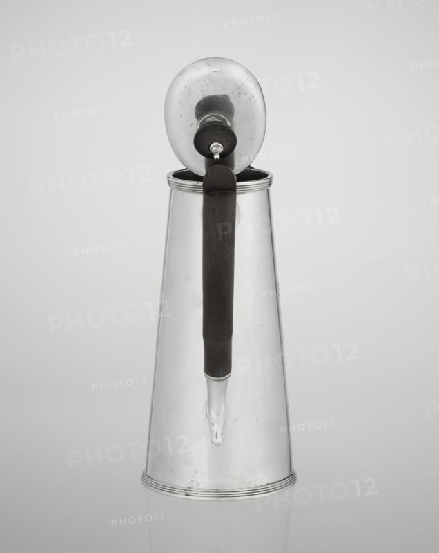Coffee pot, maker: Barnard, Edward & Sons Ltd London; goldsmith's firm; fl. ca. 1680–, maker: Clark, Alfred Ltd London; goldsmith's firm and sellers; fl. 1898–1934; conical coffee pot with hinged lid, slightly arched and flattened at the top, topped with a wooden handle made; spout short, with two sleeves on the axis for attaching a wooden handle added contemporarily; on the mantle engraved monogram tied HH under a ducal mitre, dated 1890/1891; material: silver with wooden handle; function: coffee ware; place: London, England, Great Britain; vessel dimensions: height 17.3 cm, width 11 cm, depth 8.4 cm; weight 627 g., A tall metallic pitcher with a conical shape stands against a light gray background; it has a reflective silver surface showing subtle scuffs and spots, a dark brown vertical handle attached near the top and extending down toward the spout, a rounded lid with a knob that is open and tilted back, and a short tapered spout near the base.