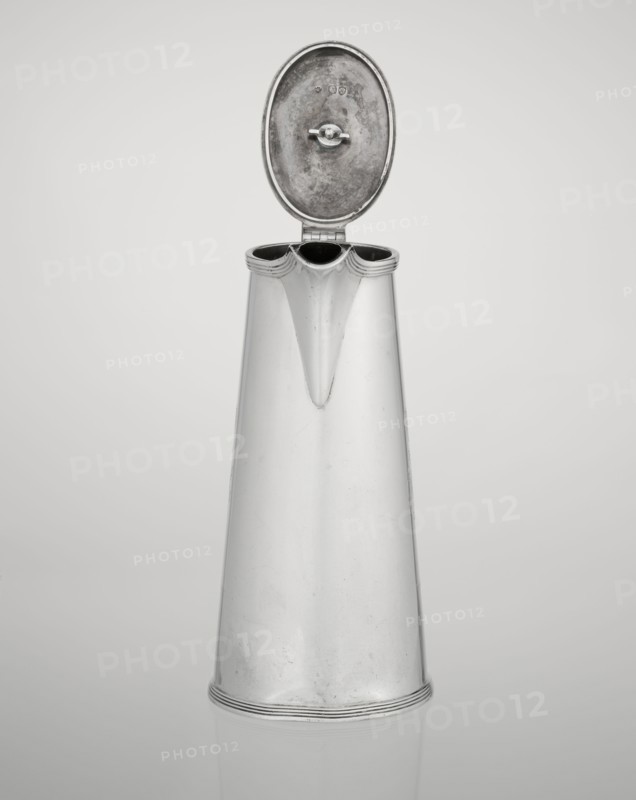 Coffee pot by Barnard, Edward & Sons Ltd London; goldsmiths; fl. ca. 1680–, and Clark, Alfred Ltd London; goldsmiths and sellers; fl. 1898–1934. Conical coffee pot with hinged lid, slightly arched and flattened at the top, topped with a wooden handle made; spout in the form of a short spout; on the axis two sleeves for attaching a wooden handle added contemporarily. Engraved monogram tied HH under a ducal mitre, dated 1890/1891. Silver vessel, England, London. Height 17.3 cm; width 11 cm; depth 8.4 cm; weight 627 g., A tall metallic pitcher with a hinged oval lid open at the top, showing a rounded interior surface and a small fastening knob; the pitcher has a narrow spout formed by the tapering front and a scalloped rim with a few curved grooves, and it stands on a round base with subtle concentric ridges; the finish of the object is reflective silver with areas of darker patina and light scuff marks, set against a smooth light gray to off-white background that creates a faint mirrored...