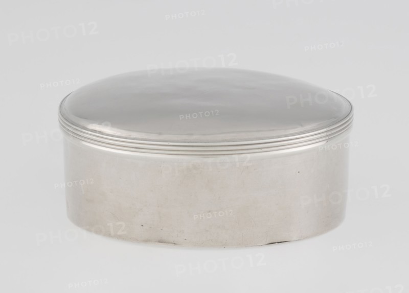 Toilet box; maker: Edward Fernell fl. 1779–1796?, goldsmith; round box, smooth with slightly domed lid edged with a profiled band; 1792/1793; Georgian/Classicism/George III style; England, London, Great Britain; material: scrap gold?; function: container / toilet accessories; dimensions: height 4.2 cm, diameter 8.2 cm, weight 115 g., A smooth, rounded metal container with a domed lid resting on a cylindrical base, both surfaces showing a reflective silver finish with subtle variations in tone and faint surface marks; the lid features a set of raised concentric ridges near its lower edge; the background is a soft, even light gray and white gradient.