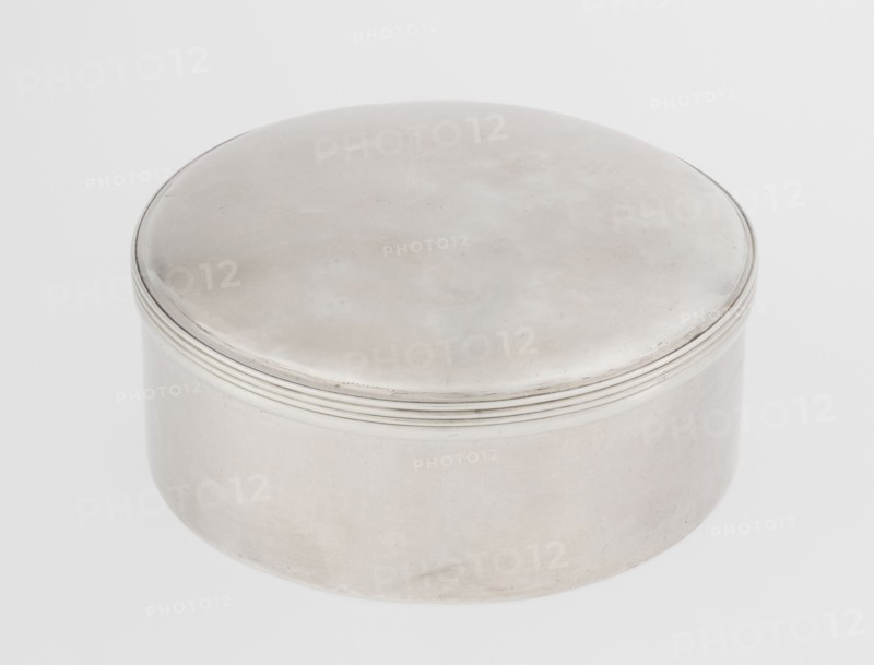 Toilet box by Edward Fernell fl. 1779–1796?, goldsmith; round, smooth with a slightly domed lid edged with a profiled band; Georgian/Classicism/George III style; 1792–1793, London, England, Great Britain; function: container/toilet accessories; height 4.2 cm, diameter 8.2 cm, weight 115 g., A round metal container with a smooth domed lid and slightly raised concentric ridges near the rim, showing a metallic silver surface with subtle variations in tone and faint marks; the background is a pale off-white.