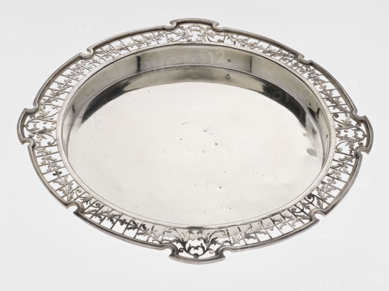 Round tray, circular silver tray with smooth mirror, slightly raised, openwork collar decorated with plant tendril, irregularly cut edge bordered with profiled band, openwork, plant tendril motif, 1922/1923, Sheffield, England, Great Britain; table accessory; height 1.8 cm, width 27.1 cm, depth 18 cm, weight 576.5 g., A round silver tray with a polished central surface and a raised rim, featuring an ornate openwork border with decorative cutouts and scrolling motifs; the visible colors are silver tones and subtle gray reflections against a white background.