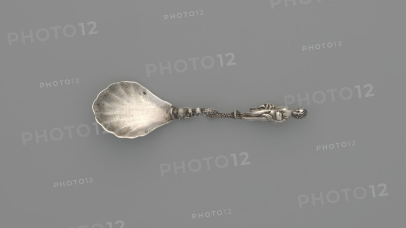 Decorative silver spoon with a shell-shaped scoop and handle formed by a solid dolphin supporting a naked woman who covers her breasts with her left hand and holds a shawl to cover her womb with her right; decorated with Venus and dolphin motifs; maker: François-Auguste Boyer-Callot fl. 1865– ; 4th quarter of the 19th century, Paris, France; cutlery decorative, length 8.5 cm, width 2.4 cm, weight 10 g., A metallic spoon with a scallop-shaped bowl and a decorative handle featuring a sculpted human figure and ornate twisting elements, shown against a uniform gray background; visible colors include silver tones of the spoon and various shades of gray in the background.