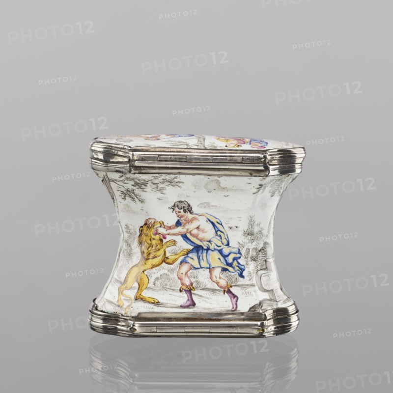 Double snuffbox, enameller LZ France?, fl. ca. 1700. Double-sided snuffbox, tall, narrowed halfway up; slightly bulging lids, framed by silver, profiled fittings, white-enameled, decorated with colourful scenes from the story of Samson depicted against a landscape painted in grisaille. Sides: two representations — Samson going to the Philistine city of Timna, shown the way by three women, and Samson fighting a lion. Lids: Samson carrying the door the city gate to the top of the mountain opposite Hebron, and Samson taking honey from the lion's mouth. Reverse of the lids: two landscapes with architecture painted in grisaille and colourful flowers painted in the bottoms. Early 18th century, France, enamelling; smoking accessory. Dimensions: height 7 cm, width 7.7 cm, depth 4.7 cm., A small hinged box with a curving, hourglass-shaped body and metal trim, decorated with a painted scene showing a man wearing a blue draped garment and pinkish footwear grappling with a yellow lion; the painted...