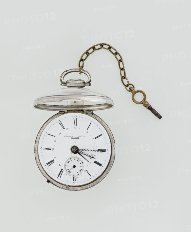 Pocket watch with key, Eardley Norton fl. 1770–1792; born 1728, died 1792. Repeater pocket watch in two silver cases: smooth outer case; inner case with framed glazed lid and mechanism cover engraved with an openwork floral/acanthus twig, winding hole, and bell. White enameled dial with black Roman hour numerals, minute scale marked with dashes, calendar with Arabic numerals, three steel hands hour and minute in openwork weave; third straight for day of month. Small seconds subdial at bottom with Arabic numerals. Dial signed “EARDLEY NORTON / LONDON.” Movement: gilded brass circular plates connected by pillars, spring-powered drive, spindle escapement; lower plate with openwork crown richly decorated with acanthus tendrils and engraved acanthus volutes; cut-out reserve engraved “Eardley / Norton London.” Preserved winding key on chain. Third quarter of the 18th century; case made in Germany; movement by London maker. Timepiece. Dimensions: height 8 cm; width 6.2 cm; dial diameter 5.3 c...