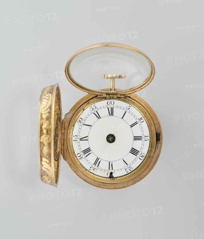 Pocket watch in case; maker: Cradelle, M. fl. ca. 1750; role: watchmaker; decoration: mythological scenes; style: rococo; type: watch in double case with outer case covered with lizard, with riveted rosette; date: mid-18th century; place of origin: London, England, Great Britain; object type: timepiece; dimensions: height 6 cm, width 4.5 cm, diameter dial 3.5 cm., A circular pocket watch with an open ornate cover and open glass lid sits against a pale gray background, the watch case and cover showing a gold color with decorative embossed patterns on the inner rim of the cover, the inner face of the watch being white with concentric circular designs and black radial markings, and small dark metallic components at the center and edge; overall visible colors include gold, white, black, dark metallic, and pale gray.