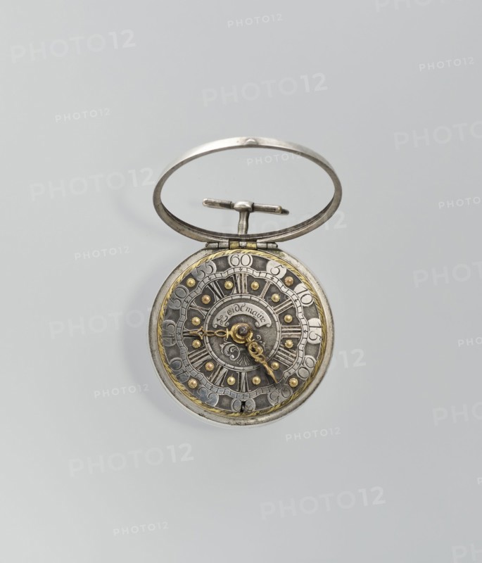 Pocket watch by Joseph Zeidlmayr fl. first half of the 18th century. Watch in a double case: outer case with a framed dial and a repoussé depiction of the Crucifixion with Mary and St. John on the back, surrounded by a border of eight C-shaped sections and ornamental decoration. Smooth silver inner case; silver dial with Roman numerals for hours separated by gold dots and Arabic minute numerals. Reserve bears the signature of the watchmaker Zeidlmayr. Inside, the movement cover has a cutout revealing a bun. Movement marked: Breslau / Joseph Zeidlmayr. On the inside of the case: a negative MS mark, a negative mark and a possible illegible goldsmith's mark rosette?, and two numbers—markings likely made by repair watchmakers. 1st half of the 18th century; Silesia; timepiece., An open pocket watch with a metal ring and hinge, showing a circular ornate face with metallic tones of silver and gold, a dark gray inner dial, and a few decorative raised studs in gold; the watch hands are intricat...