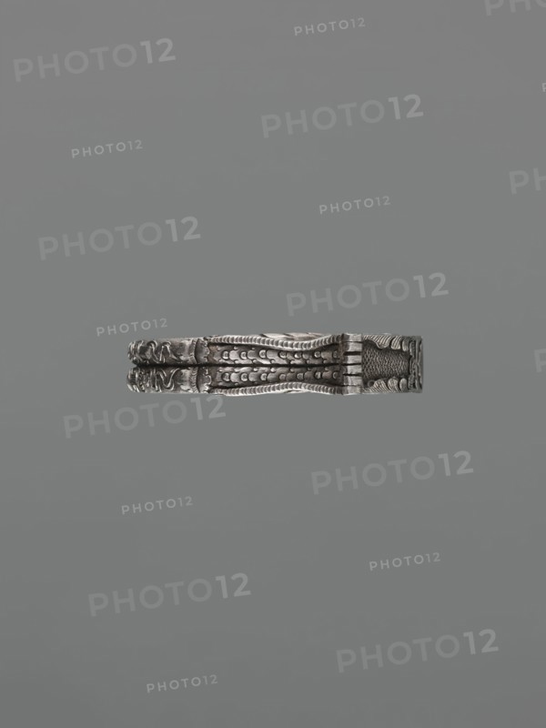 Bracelet, scrap-purchase provenance, Chinese and Mongolian art influences; body/hand ornament fashion accessory depicting dragons and dragon with pearl motif, hundred antiquities baigu ornament; Chinese culture; 19th century ; China, Mongolia ; jewelry; height 8.0 cm, width 9.0 cm, weight 281 g, A horizontal metallic object with intricate raised patterns and textured surfaces floating against a uniform gray background, showing tones of silver and dark gray with areas of subtle shadow and highlight.