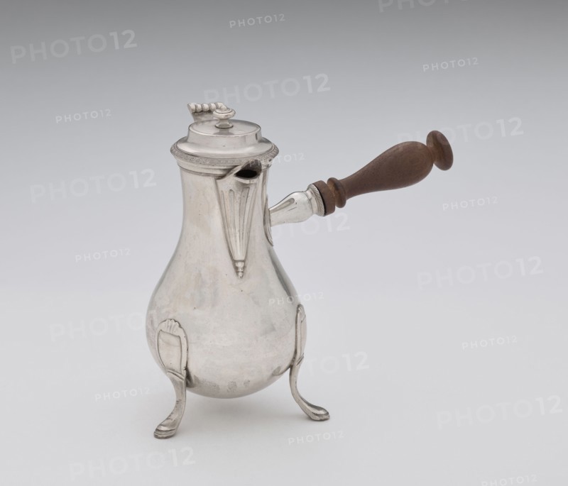 Coffee pot by F. Picard active ca. 1798–ca. 1809. Scrap-purchase; coffee pot, tableware item, jug. Made in Paris, France, ca. 1798–1809. Vessel; height 46.0 cm, width 8.5 cm, depth 8.5 cm, weight 248.2 g., A pear-shaped metal pot with a reflective silver surface stands on a group of three curved legs, each leg ending in a flattened foot; the pot has a short ornate spout and a hinged domed lid with a decorative finial, and a turned wooden handle attached to the side extending outward; visible colors include silver tones on the metal, brown on the wooden handle, and neutral gray and white in the background.