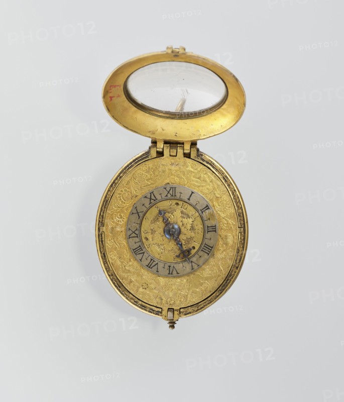 Pectoral watch, Stosch, Israel fl. 1st half of 17th century watchmaker, baroque, floral ornament, grotesques. Pectoral watch in an oval case, frame with a circular glazed cut-out, beneath which a dial with a silver ring with hour numerals. Frame decorated with an engraved tendril. Underside open-work, with a motif of a winged bust passing at the bottom into a tendril; around it is a tendril motif. Openwork sides of the case with a tendril motif. Mechanism with a striking device, signed I. STOSCH. 17th century; timepiece; height 5.3 cm, width 3.5 cm., An open oval pocket watch with a hinged lid revealing a domed glass and a metallic inner rim, both showing gold and clear tones; the watch case and face are gold with intricate engraved floral and scroll patterns, and an inner circular ring in a darker metallic color contrasts with the gold; ornate blued steel hands sit at the center with a small decorative central element, and the overall palette includes gold, blued steel, clear glass, a...