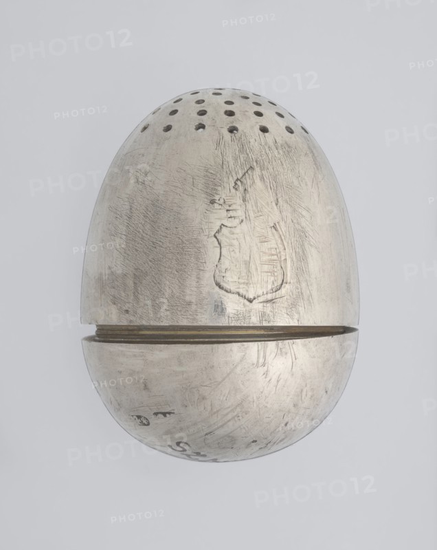 Salt cellar, scrap - purchase; spices vessel, salt vessel, spice vessels; 19th century; St. Petersburg, Russia; vessel; height 4 cm, width 3.1 cm, A metallic, egg-shaped object set against a light gray background, with a top half featuring a row of small round perforations and a horizontal seam where the two halves meet; the metal surface is worn and scratched with visible scuff marks and textured abrasions, showing areas of darker gray patina and lighter silvery highlights, and a faint irregular shaped impression on the upper half; overall colors visible are silver, light gray, and darker gray.