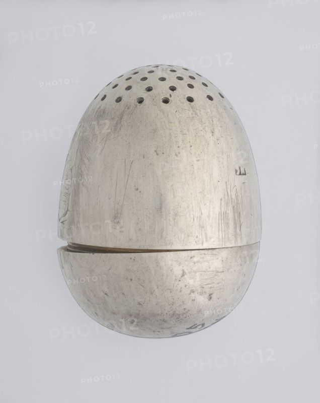 Salt cellar, scrap-purchase; spice vessel for salt; 19th century; St. Petersburg, Russia; vessel; height 4 cm, width 3.1 cm, A metallic egg-shaped object photographed against a pale gray background, with a few rows of round perforations near the top; the metal surface shows many scratches, scuffs, and worn areas giving a textured appearance, and there is a visible seam where the top and bottom halves meet; the colors visible are shades of silver, gray, and faint darker marks on the metal, with the background in light gray.