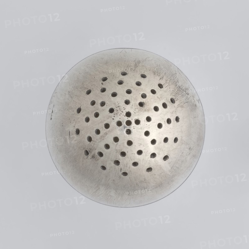 Salt cellar;, scrap - purchase; spices vessel; salt vessel; spice vessels; 19th century; St. Petersburg, Russia; vessel; height 4 cm; width 3.1 cm, A circular metallic object with a slightly domed surface and a weathered, scratched texture, featuring a pattern of several small round perforations arranged across its central area; the metal shows tones of silver, gray, and muted off-white with darker shadowed holes, all set against a pale gray background.