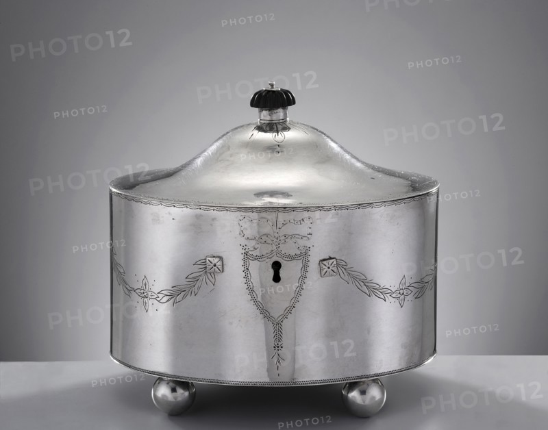 Classicist sugar bowl by Christian Jacob Haase fl. 1797–1810, Late Classicist style. Oval sugar bowl with a centrally arched hinged lid topped by a wooden knobbed dome; front features a keyhole set in a dot-engraved cartouche from which festoons of lanceolate leaves extend. Maker likely from the youngest generation of the Haase family—Christian Jacob, son of Johann Jakob Haase II; became master in 1797 and left Gdansk with his family in 1810. The HAASE namemark, stamped in a rectangle with rounded corners on this bowl, may be attributable to him though it differs from his father’s mark. Materials/subject: sugar vessel with festoon ornament, classicism. Date: 1799. Place: Gdansk, Royal Prussia Poland. Dimensions: height 13.7 cm, width 15 cm, depth 11.5 cm; weight 540 g., A rounded metallic container with a domed lid and a small dark knob on top sits on a flat surface; the container is silver in color with engraved decorative garlands and floral motifs along its curved sides, a keyhole-s...
