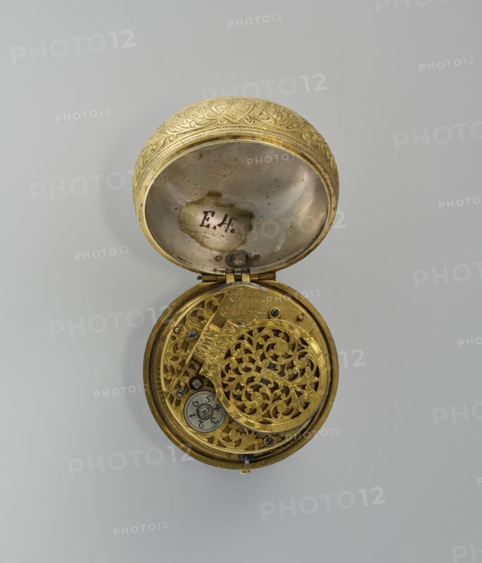Pocket watch by Jacques Marcet fl. ca. 1725–ca. 1750. Gilded silver pocket watch, almost spherical, in a double case; enameled numerals on the dial. Cases decorated with plant decoration: inner case with flowers in a vase in a reserve formed by a ribbon that on the outer side forms heart-shaped loops with floral sprigs between them. A strip of plant-floral tendrils on the side of the case. Outer case with a flower sprig in a circular central reserve surrounded by an interwoven ribbon and floral sprigs in the fields. Movement signed Jacques/Marcet and has an openwork bow. Inside both cases engraved number E. 4 unidentified. Engraved case decoration stylized in a Middle Eastern style; possibly intended for the Turkish market. Watchmaker uncertain; possibly worked in England if a Huguenot. 2nd quarter of the 18th century, France . Timepiece. Dimensions: height 6.5 cm, width 5.5 cm, depth 4 cm. Style: classicism; decorative vases; flowers., A round, opened metal object with ornate, carved ...