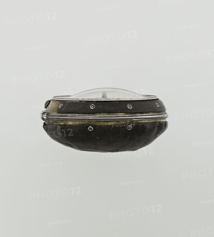 Pocket watch by John Bushman 1692–1720. Silver pocket watch in three cases: outer case covered with leather, rim decorated with studded silver rosettes; middle and inner cases plain. Underside of the inner case stamped with the casemaker's initial H and the number 3081; transparent lid. Silver champlevé dial with Roman numeral hour markers and Arabic minute markers in oval reserves on a matte background; central circular reserve with the watchmaker's signature on two semicircular plates reading BUSHMAN and LONDON; date window at the bottom. Steel hands, openwork hour hand. Movement with a plate skeleton, spring drive, worm gear, and Gall chain; spindle escapement. Gilded lower plate with an openwork English-style bun in the form of a wreath filled with acanthus tendrils and an openwork grid, connected by a mascaron mask with an openwork bun foot. Hair adjustment via a rotating silver-plated dial with a scale I–VI. Engraved on the plate in italics: Jn Bushman 3081 / LONDON. Dated c. 170...