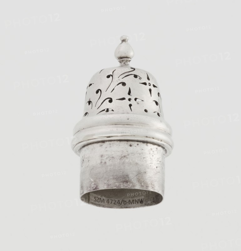 Powdered sugar bowl, pear-shaped on a circular profiled foot, with a domed openwork cover topped with a bowl. Edge of the foot and the top rim decorated with astargal. Openwork, sugar vessel; dish. Maker: Burbidge, Richard 1847–1917, goldsmith. Date: 1913/1914. Materials/technique: scrap; purchase provenance. Dimensions: height 15 cm, diameter 5.9 cm, weight 152 g., A metallic object with a rounded top and a finial sits against a pale background; the top section has decorative cutout patterns and a smooth band separating it from a cylindrical lower section that shows surface scratches and tarnish. The visible colors are silver, gray, black from the cutouts and tarnish, and a light off-white background.