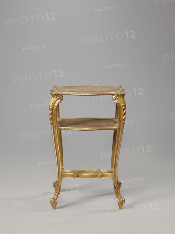 Side table, equipment of representative buildings of the Republic of Poland 1918–1939, unknown origin, plant decoration with acanthus ornament and volutes, neo-rococo style, 3rd quarter of the 19th century, Warsaw; furniture, table; height 77.3 cm, width 50 cm, depth 40 cm., A small ornate table with a gold finish stands against a plain light gray background; the table has a rectangular top with curved edges, a lower shelf, four slender cabriole legs with carved scroll and acanthus details, and a decorative stretcher joining the legs, all in gold tones with subtle darker shading.