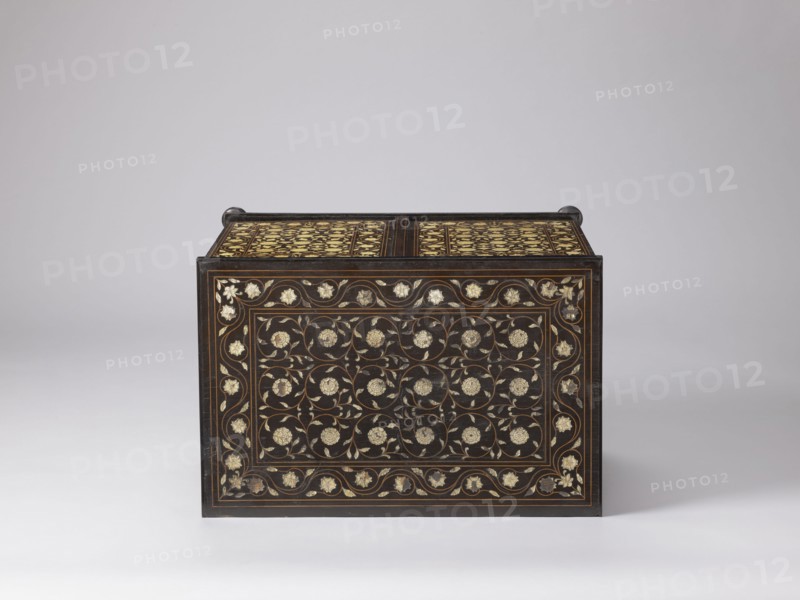 Cabinet, plant decoration, columns, rosettes, early 20th century, India, Europe, piece of furniture, storage piece; height 46.2 cm, width 63 cm, depth 43 cm, A rectangular dark wooden chest with ornate floral inlay sits against a light gray background; the front and top surfaces display a repeating pattern of floral motifs and curling vines in pale cream and gold tones set within thin brown borders, and the chest has small rounded dark handles at the top corners.