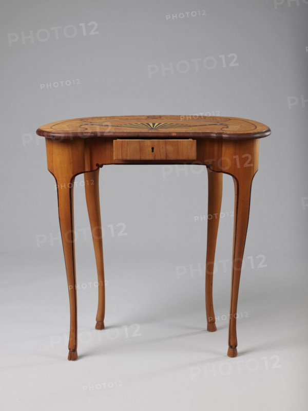 Table, Kidney-shaped auxiliary table, ca. 1730–1750, Saxony . Supported by four slender, slightly curved S-shaped legs framed and bound with a rosewood ribbon; feet shaped as hooves, stained black. Front frame concave with a small central drawer. Tabletop decorated centrally with a fan enclosed by four fields separated by an irregular ribbon and a narrow crosswise frame; fan setting inlaid with mother-of-pearl rosettes and bound with tin veining, lower part of fan showing alternating light and dark areas. Tabletop edge veneered with yew solid wood. Mortise lock, single-bolt with brass plate. Furniture — table. Height 72.5 cm, width 71.5 cm, depth 46.2 cm., A wooden table with a light brown finish and darker brown edging stands on slender curved legs; the tabletop is oval with a decorative inlay pattern radiating from the center in darker and lighter wood tones, and there is a small centered drawer beneath the top. The visible colors include light brown, dark brown, and subtle variation...