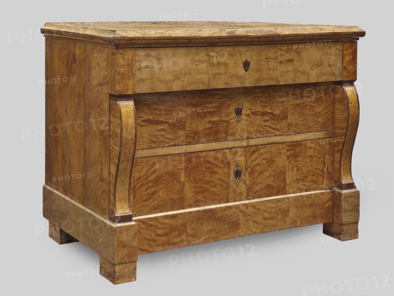 Chest of drawers, repossession provenance; Biedermeier style. Rectangular four-drawer chest with a wooden top with profiled edge sima, platka, and quarter round, on block legs; veneered with wavy birch. Front corners framed in the central section by volute consoles veneered with burl bird's-eye maple?. The upper and lower drawers extend out, the lower one set in the plinth. On the faces of the three upper drawers are inlaid dark disc-shaped lock plates. Backs are board, chamfered, recessed from below. Locks of the three upper drawers are applied-mortise, steel, single-bolt. Dated 1830–1840. Central Europe, possibly Poland. Piece of storage furniture. Height 85.5 cm; width 119 cm; depth 61.2 cm., A wooden chest of drawers with a warm brown and golden grain finish is shown against a pale gray background; the piece has a rectangular top with a slightly projecting molded edge, a straight front with two curved vertical carved supports on either side, and a plinth base with short block feet....
