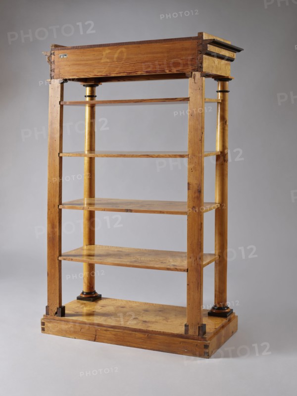 Shelf unit, Biedermeier, architectural elements, pilasters, birch, wall-mounted, with four rectangular shelves supported by four corner supports columns at the front, pilasters at the back mounted on a platform, supporting the profiled architectural cornice of the upper wreath. Columns with smooth shafts. Plinths, bases, and capitals of the columns stained black. Shelves with a striped rim creating a small, full gallery. Plate platform, on low block legs/pads, ca. 1830, Central Europe, piece of furniture for presenting objects; height 168 cm, width 105.5 cm, depth 49.5 cm., A wooden shelving unit with a natural brown finish standing against a neutral gray background, featuring a rectangular base and a top with darker brown trim, vertical posts and a pair of cylindrical columns with a yellowish-brown tone and dark brown ring accents, several flat shelves with visible wood grain, and small darker wood blocks at the base corners; colors visible include various shades of brown, yellowish-b...