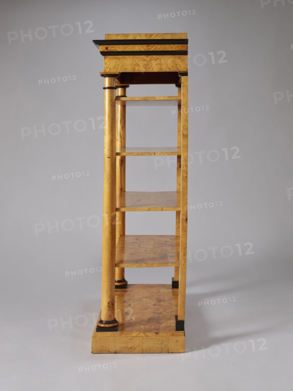 Shelf unit, columns architect, Biedermeier style, architectural elements, pilasters architect, birch, wall-mounted, with four rectangular shelves supported by four corner supports columns at the front, pilasters at the back mounted on a platform, supporting the profiled, architectural cornice of the upper wreath. Columns with smooth shafts. Plinths, bases, and capitals of the columns stained black. Shelves with a striped rim creating a kind of small, full gallery. Plate platform, on low block legs-pads, ca. 1830, Central Europe, piece of furniture for presenting objects, height 168 cm, width 105.5 cm, depth 49.5 cm, A tall wooden shelving unit photographed against a plain light gray background, showing a side view with a vertical column and a series of open shelves; the wood has a warm golden-brown tone with visible grain and darker brown knots, and there are small areas of black trim or accents on the column bases and shelf edges; the top has a slightly darker horizontal molding, and ...