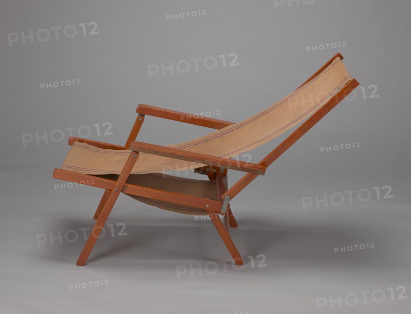 Deckchair, Polish Timber Industry, Czerski and Jakimowicz furniture factory; 1929–1939,  furniture factory author, lounge furniture, beach furniture, garden furniture. Folding deckchair constructed from two different-sized rectangular frames: the backrest smaller and the seat larger, connected by hinges, with canvas stretched over them. The frame elements with the exception of the turned rear leg connector and the doubled front seat stile are angular. The seat frame is supported on its shorter sides by two folding legs connected by a connector, the front extended into armrest supports. The armrests have hinges adjustable in three positions. Salmon-colored canvas fabric with vertical orange stripes framed by narrow blue stripes; attached to the underside of the upper backrest frame and the rear seat frame, sandwiched between the two front seat frames. Originally the deckchair was equipped with a separate footrest. 1938–1939. Lviv place of origin. Piece of furniture, seating furniture. H...